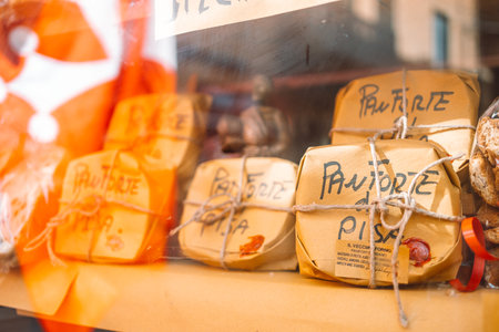 Pisa, Italy - March 18, 2023: Close-up of Panforte di Siena in festive paper packaging for sale on the counter of a shop window. High quality photoのeditorial素材
