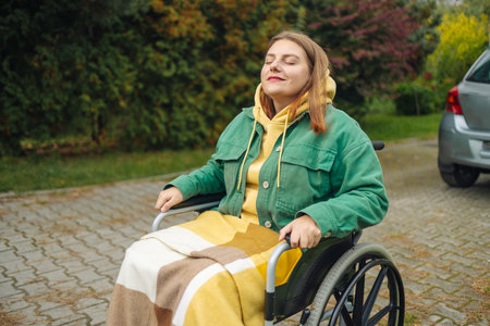 Happy smiling cheerful Caucasian woman in stylish clothes on a wheelchair relaxing alone in autumn...