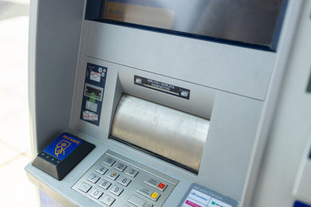 Silver automatic teller machine hanging on a gray concrete wall. High quality photo