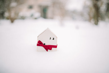 Merry Christmas and 2024 happy new year banner with small toy model house on a white snow background. Miniature white toy house model . High quality photoの写真素材