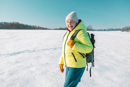 North 60s senior woman relaxing on the hill. Woman drinking hot tea from thermo cup and enjoying panorama city park view. Happiness, winter holidays, tourism, travel and people concept.の写真素材