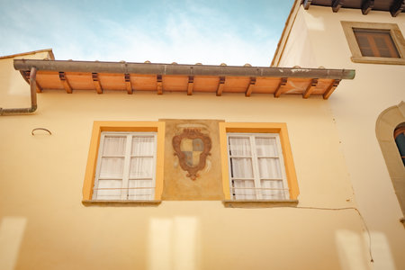 Two vintage windows on a bright orange wall. Exterior facade of historical house with apartments in Florence, Italy. Urban vintage background. High quality photoの写真素材