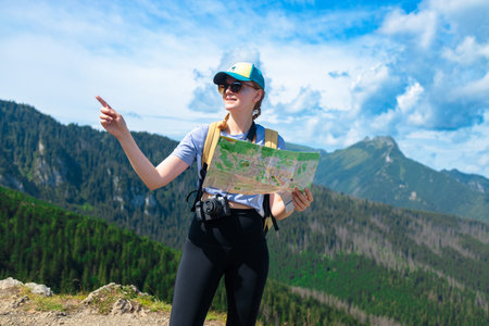 Shot of a young lost woman holding a map while taking in the view from the top of a mountain. Woman...