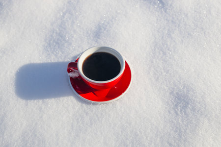 Red ceramic cup of espresso coffee stand on the snow on snow background of a winter landscape. A walk in the fresh air.の写真素材