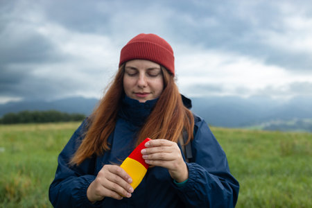 Woman using anti mosquito spray outdoors at hiking trip. Close-up of young female backpacker tourist...