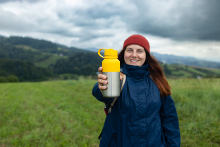 Woman traveler drinks coffee with a view of the mountain landscape. Trekking concept. Pure natural water. High quality photoの写真素材