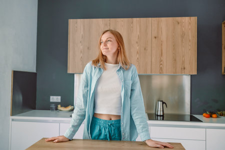 Portrait of happy Caucasian woman thinking of something standing behind countertop looking at the camera. High quality photoの写真素材