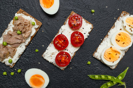 Ingredients for sandwich with boiled egg, cherry tomatoes, canned tuna, garlic and spices over black grunge background. High quality photoの写真素材