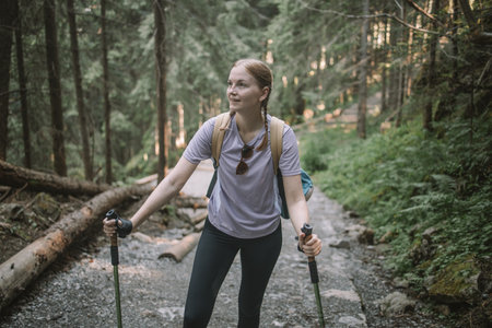 Happy woman traveler standing on the rock enjoying beautiful forest view.Female relaxing on hiking trip. Poland, Tatry, Zakopaneの写真素材