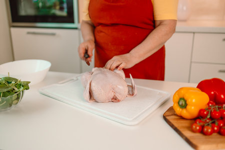 Housewife cutting chicken meat enjoy weekend morning cooking tasty dinner family husband children stand bright light kitchen indoors. High quality photoの写真素材