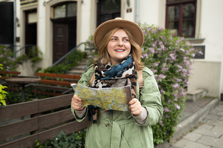 Krakow Europe travel summer tourism holiday vacation background. Attractive Caucasian young smiling girl with mobile phone camera and map in hand standing is exploring cityの写真素材