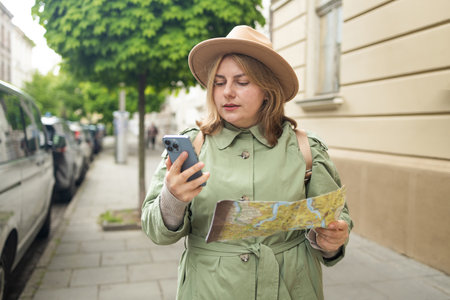 Krakow Europe travel summer tourism holiday vacation background. Attractive Caucasian young smiling girl with mobile phone camera and map in hand standing is exploring cityの写真素材