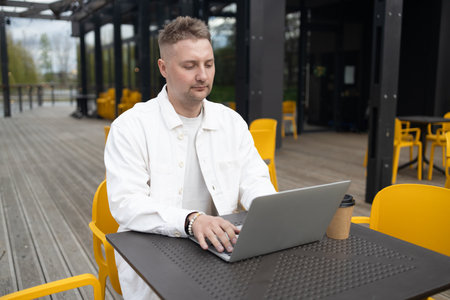 Happy successful European businessman makes a phone call on smartphone, talking and smiling outdoors sits at city cafe on city street outside. High quality FullHD footageの写真素材