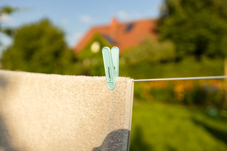 Recently washed clothes are hung along the line to dry with colorful plastic clothespins at lunchtime. Concept of everyday household items. High quality photoの写真素材