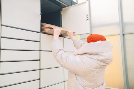 Woman putting box to automated parcel machine.の写真素材