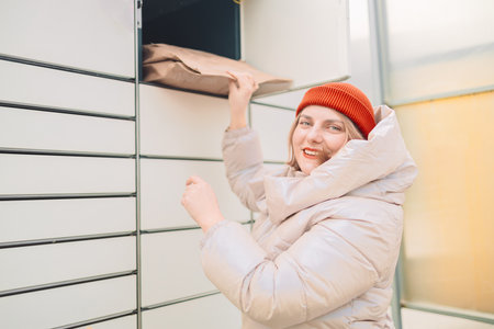 Woman putting box to automated parcel machine.の写真素材