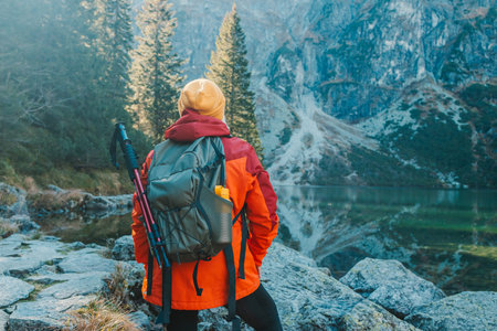 Lady tourist with a backpack standing on top of the mountain and enjoy the beautiful view of...