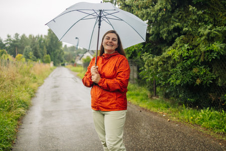 Rain umbrella, city street portrait and woman with umbrella on a sidewalk. Happy female person, raining and travel on urban road outdoorの写真素材