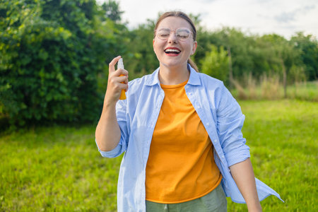 Woman spraying insect repellent or bug spray to her hand at park. High quality photoの写真素材