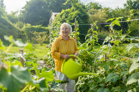 Happy 50s 60s senior woman taking care of flowers outdoors in garden, watering with can. Female preparing for preparing flowers for international women day. High quality photoの写真素材