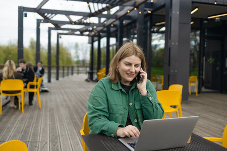 Happy successful European businessman makes a phone call on smartphone, talking and smiling outdoors sits at city cafe on city street outside. High quality FullHD footageの写真素材