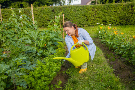 Happy 30s woman taking care of flowers outdoors in garden, watering with can. Female preparing for preparing flowers for international women day. High quality photoの写真素材