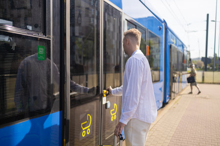 A young businessman in a stylish suit with a suitcase enters a tram. High quality photoの写真素材