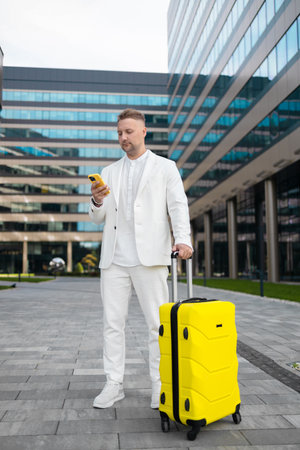 Focused young corporate worker investor businessman walking and using mobile phone outdoors near a business centre. High qualityの写真素材
