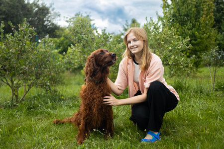 A young girl student is petting and feeding and playing with her pet dog in backyard. High quality photoの写真素材