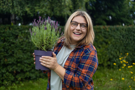 Happy woman farmer holding plastic box with fresh lavender flower herbs on countryside field. High quality photoの写真素材