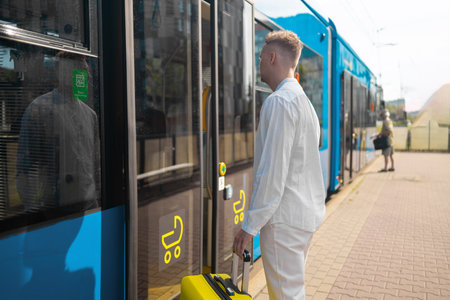 A young businessman in a stylish suit with a suitcase enters a tram. High quality photoの写真素材