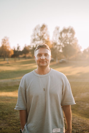 Portrait of happy Caucasian blonde man looking at camera outdoor, walking rest relax in spring green city park go down alley sunshine lawn outdoors on nature. Urban lifestyle leisure concept. High qualityの写真素材