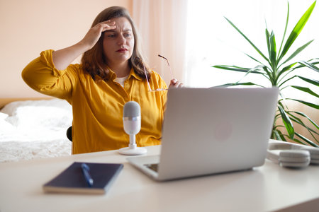 Worried fatigued mature business woman having headache at work. Tired busy 30s aged businesswoman feeling stress at home workplace looking at laptop computer in office. High quality photoの写真素材