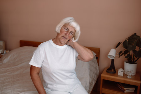 Mature woman have a shoulder pain at home office. Elderly woman shoulder pain osteochondrosis.の写真素材