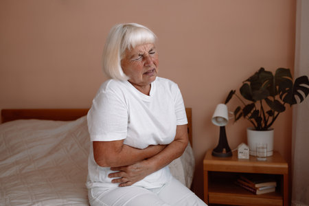 Abdominal pain in elder senior mature aging woman with stomachache illness from stomach cancer, irritable bowel syndrome, Indigestion, Diarrhea, gastroparesis or GERDの写真素材