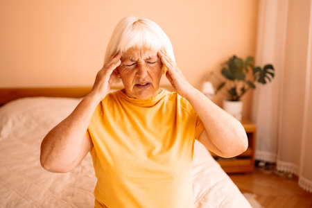 Stressed frustrated middle aged lady suffering from headache massaging temples, close up view. Tired sick mature old woman feeling unwell, touching head. Migraine pain, fatigue, stress concept. High quality photoの写真素材