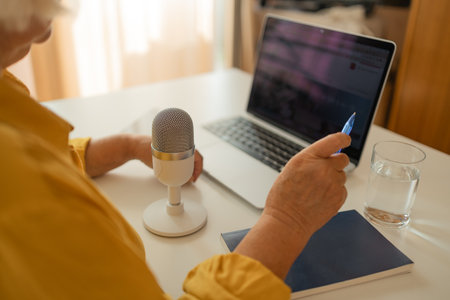 Female podcaster use smartphone and speaking with audience on microphone to recording video podcast. High quality photoの写真素材