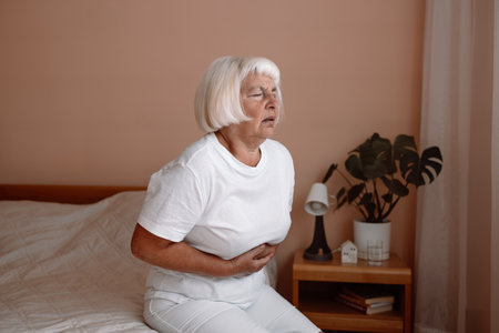 Abdominal pain in elder senior mature aging woman with stomachache illness from stomach cancer, irritable bowel syndrome, Indigestion, Diarrhea, gastroparesis or GERDの写真素材