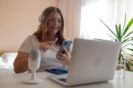 Head shot portrait smiling woman making video call to friends or relatives, using webcam, sitting on couch at home, happy young female blogger recording vlog, looking at camera, chatting online.の写真素材