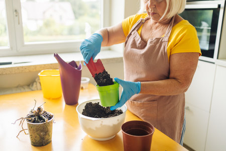 Female gardener hand holds a scoop of compost soil and pours it into a pot. Garden room gardening, Plant room, Floral decor. Planting and sowing seeds.の写真素材