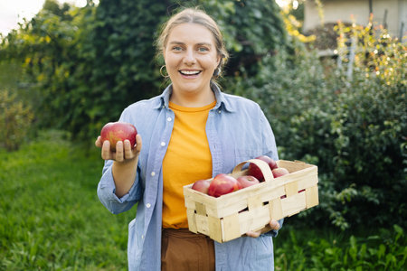 Happy Caucasian 30s farmer worker woman hands holding picking fresh ripe apples in orchard garden...