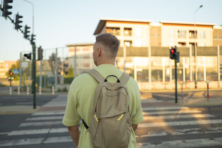 Young man waiting for traffic lights to cross street, back view