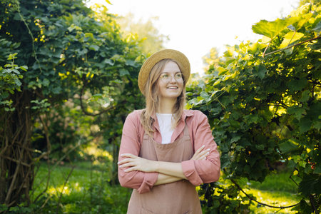 Cheerful young woman in vineyard on sunny day. Concept of healthy food and local farming. High quality photoの写真素材