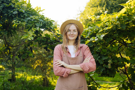 Cheerful young woman in vineyard on sunny day. Concept of healthy food and local farming. High quality photoの写真素材