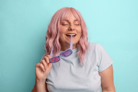 Pretty stylish young 30s woman blogger with stylish glasses posing and smiling isolated over blue studio background.の写真素材