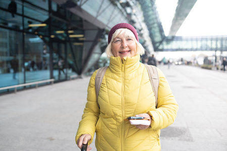 stylish pretty 50s woman traveling with suitcase in Europe in trend autumn outfit street style. High quality photoの写真素材
