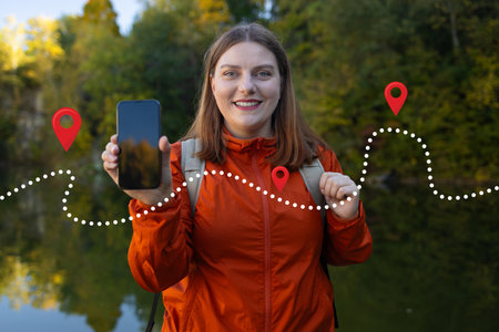 Woman using her smartphone for hiking, navigating with a map app amidst natures adventure. Girl tourist walking in forest and using smartphone gps . High quality photoの写真素材