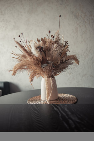 Stylish modern dried flower arrangement in a cream vase at home room. Composition with many different dried flowers in vases, on a light background.. High quality photoの写真素材