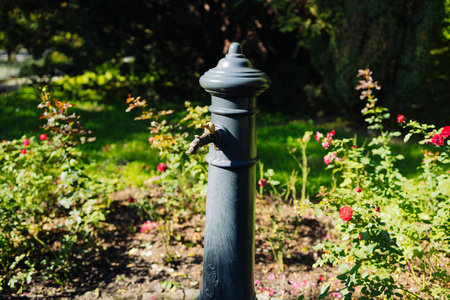 Close up of a woman hand turning on or off the faucet of vintage tap with drinking water on the city street or park. Flowing water. Selective focusの写真素材