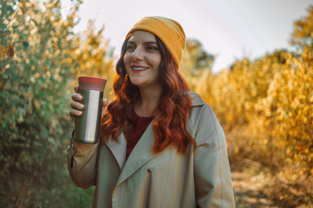 Photo of cheerful pretty relaxed 30s woman drinking coffee and smelling aroma in a park urban city street. High quality photoの写真素材